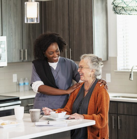 Home caregiver helps senior woman eating healthy snack