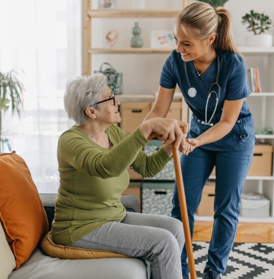 caregiver helping elder resident with a cane stand up