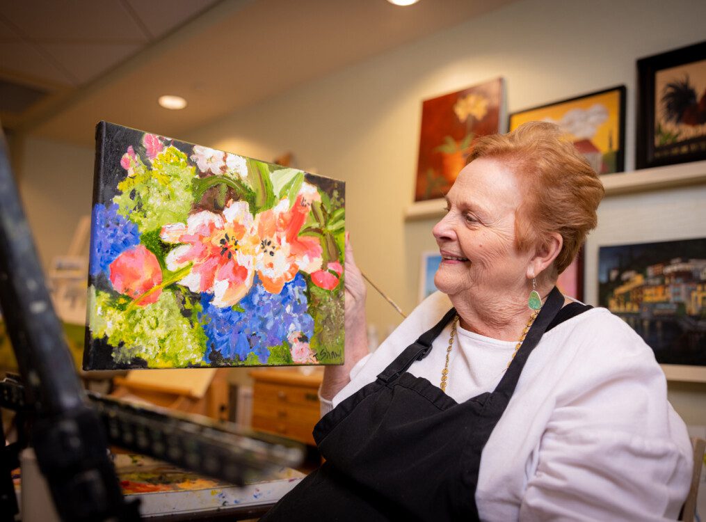 resident showing a flower painting that she just finished