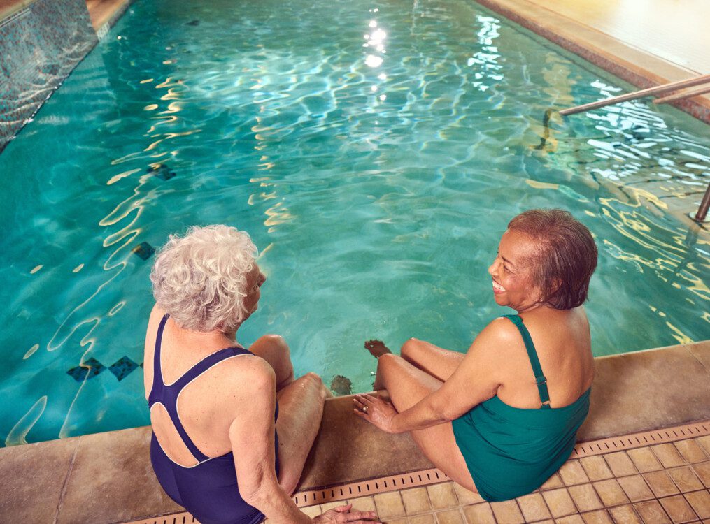 two residents talking on the side of the pool getting ready to go for a swim