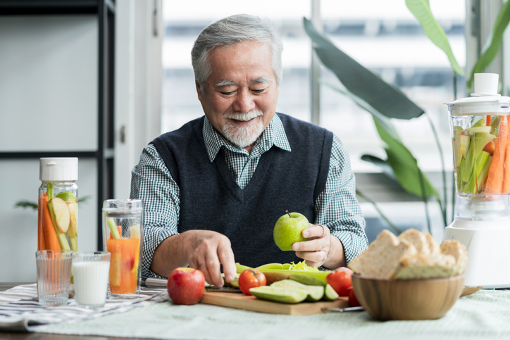 elder man chopping fruits and vegetables for a snack