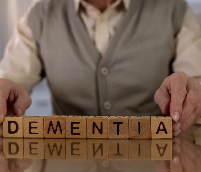 elderly man spelling out dementia with wooden blocks