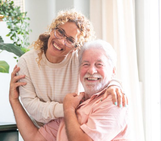 Portrait of happy middle-aged woman and senior father hugging spending time together at home