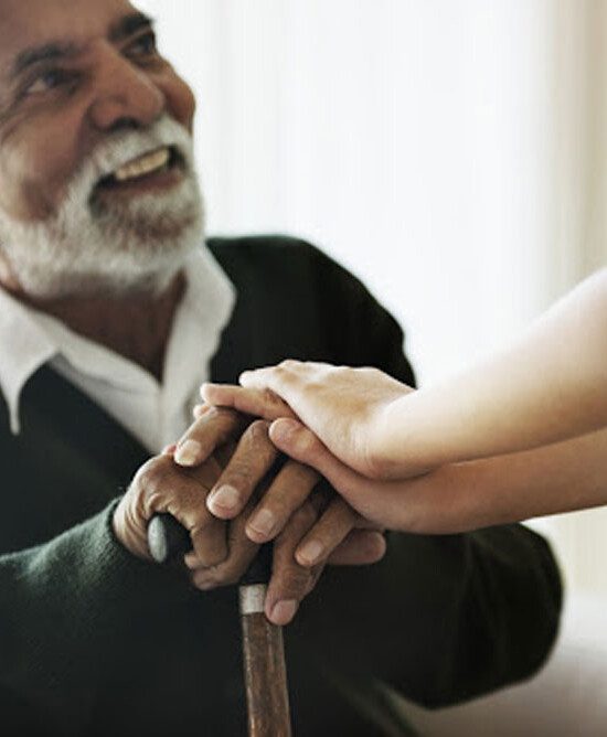 elder man with a cane sitting and holding hands with grandchild