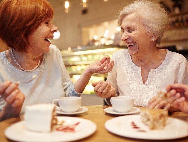 Two senior friendly females laughing during tea time