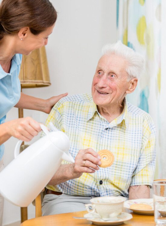 staff member offering resident a refill on his coffee