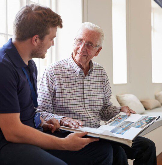 male resident showing male caregiver pictures of his family