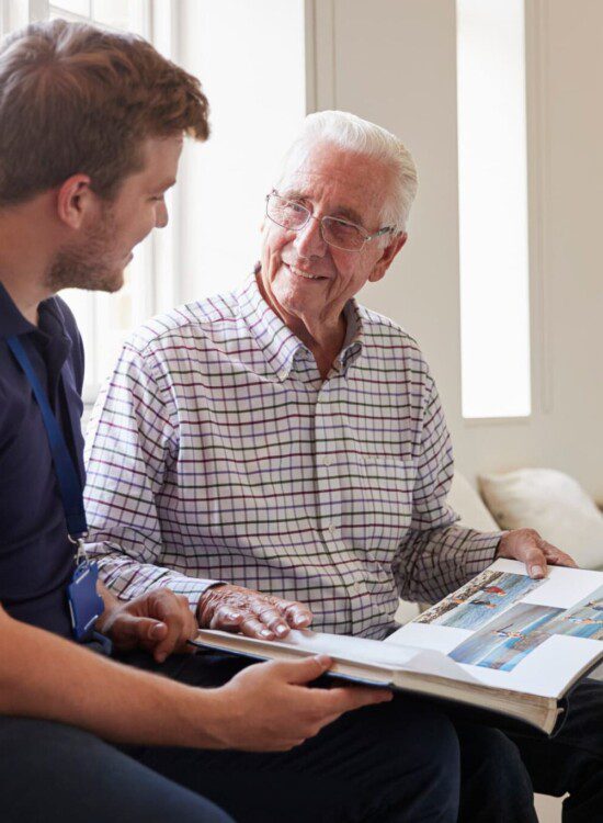 male resident showing male caregiver pictures of his family