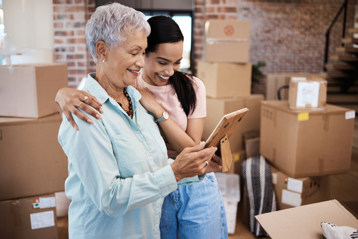 Senior woman smiling with her daughter as they pack for her move together.