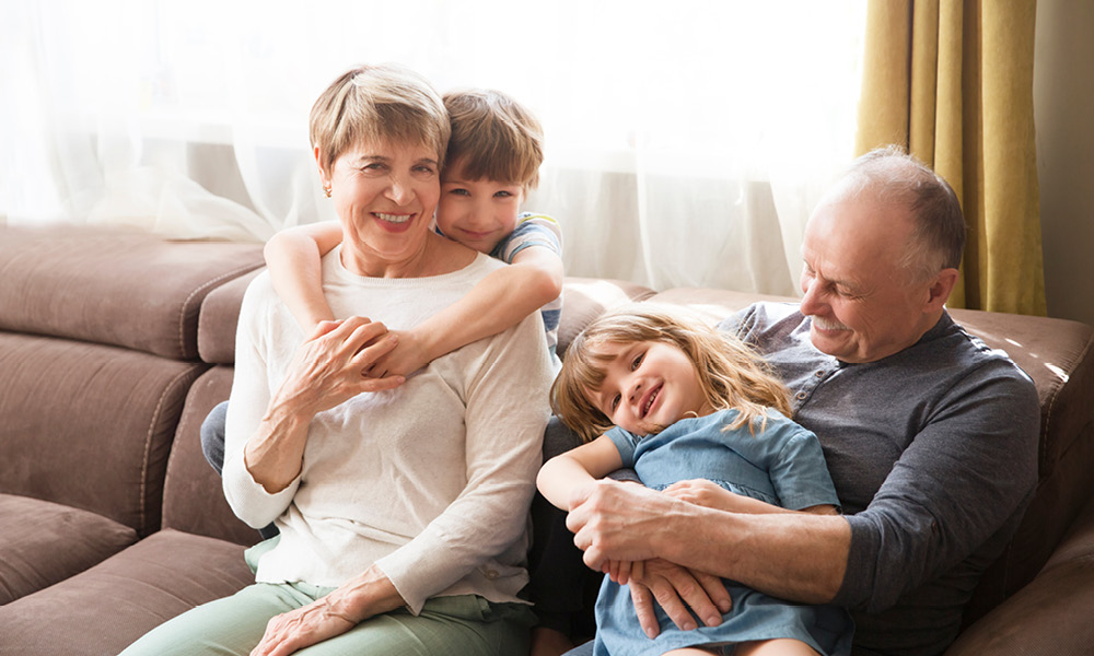 Grandparents smiling while playing with their two grand children.