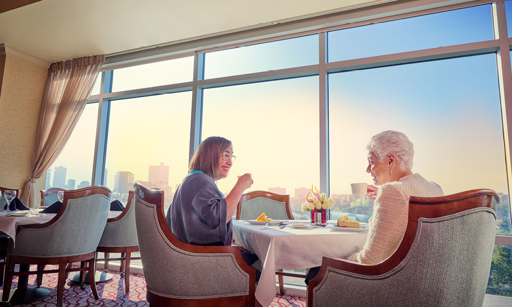 Two elderly woman smiling while having breakfast.