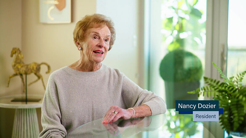 Elderly lady sitting at a table while wearing a sweater.